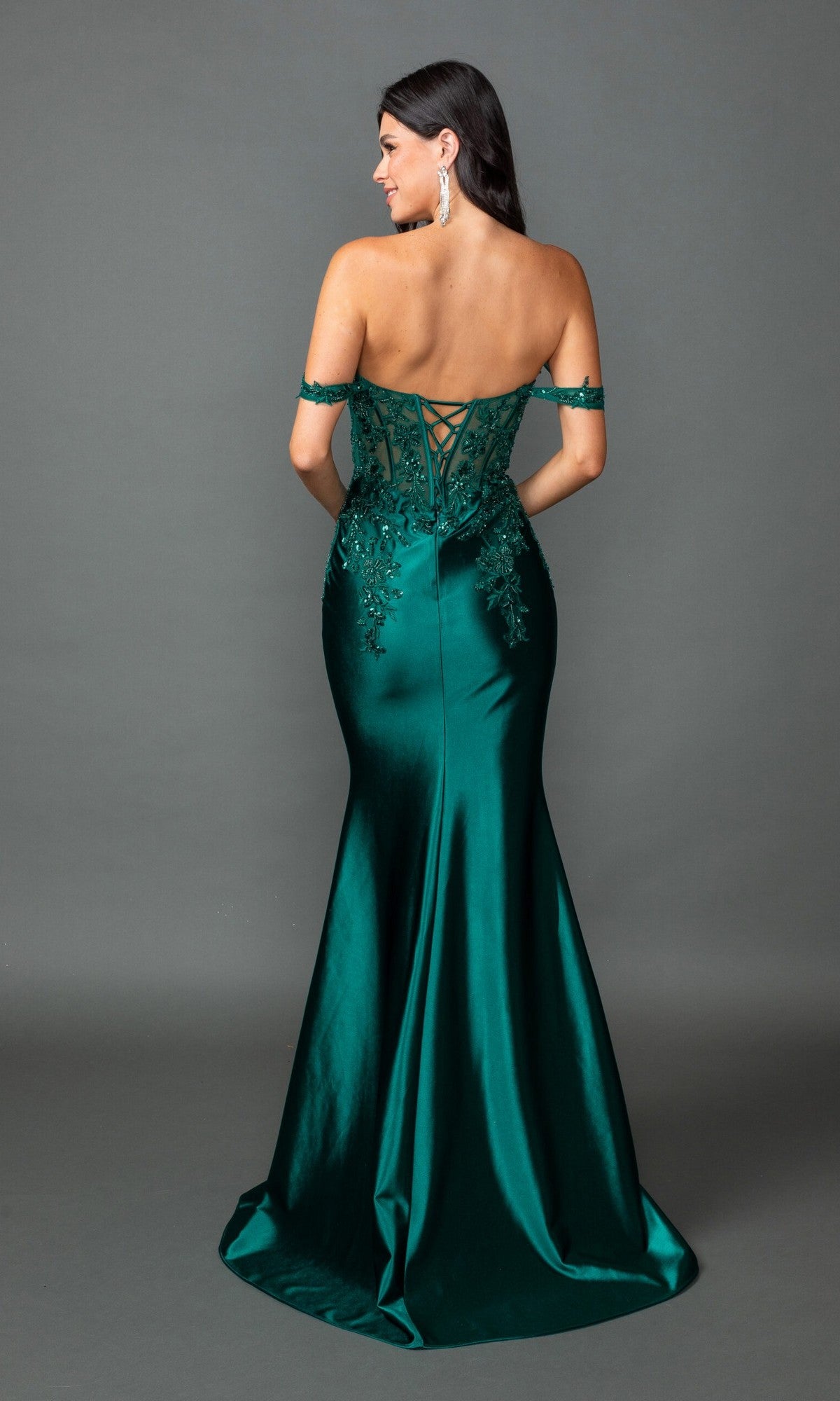 A woman stands against a plain gray background wearing the Dancing Queen 4540, a fitted emerald green long prom dress with off-the-shoulder sequin lace embroidery, lace-up back, and floral appliqué.